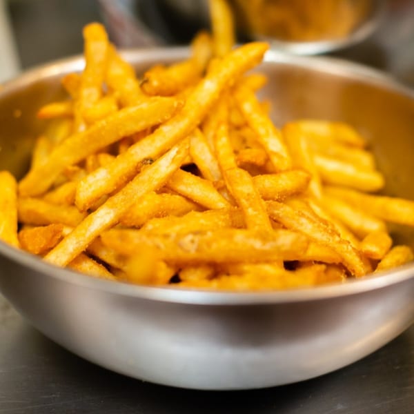 A large metal bowl overflowing with golden, seasoned french fries from Chubbfathers.