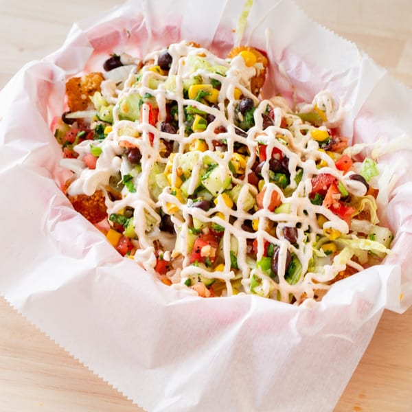 Chubbfathers' loaded tater tots with corn, black beans, tomatoes, lettuce, and white sauce.