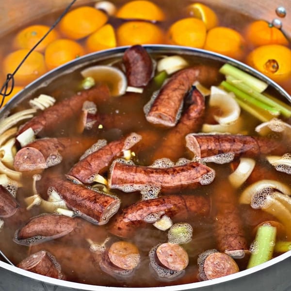 Sausage, onions, celery, and lemons simmering in a large pot of broth.