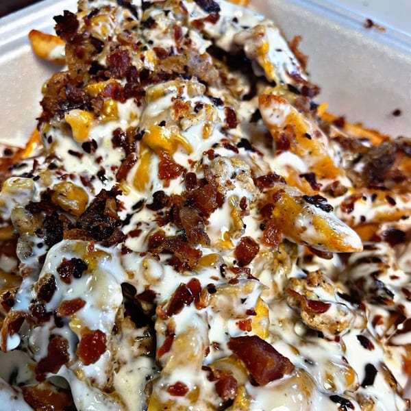 Close-up of Chubbfathers' loaded fries, topped with melted cheese, creamy sauce, and crispy bacon bits.
