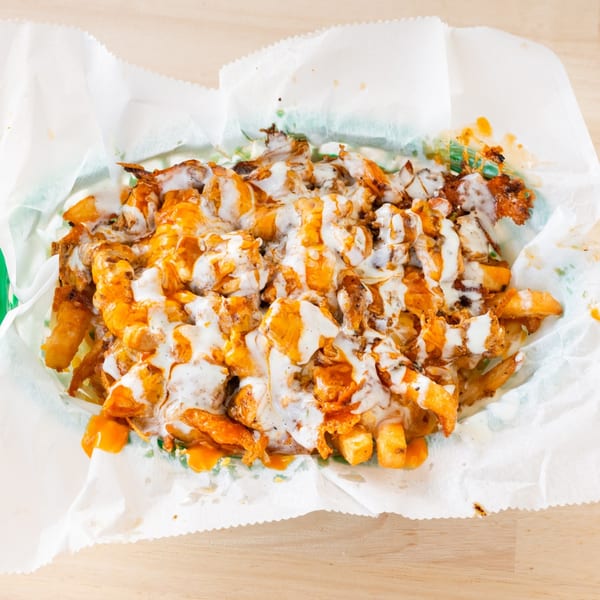 Chubbfathers' loaded fries with melted cheese, buffalo sauce, and ranch dressing in a paper-lined basket.