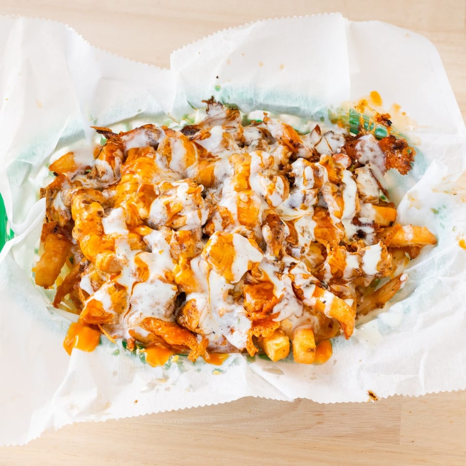 Chubbfathers' loaded fries with melted cheese, buffalo sauce, and ranch dressing in a paper-lined basket.
